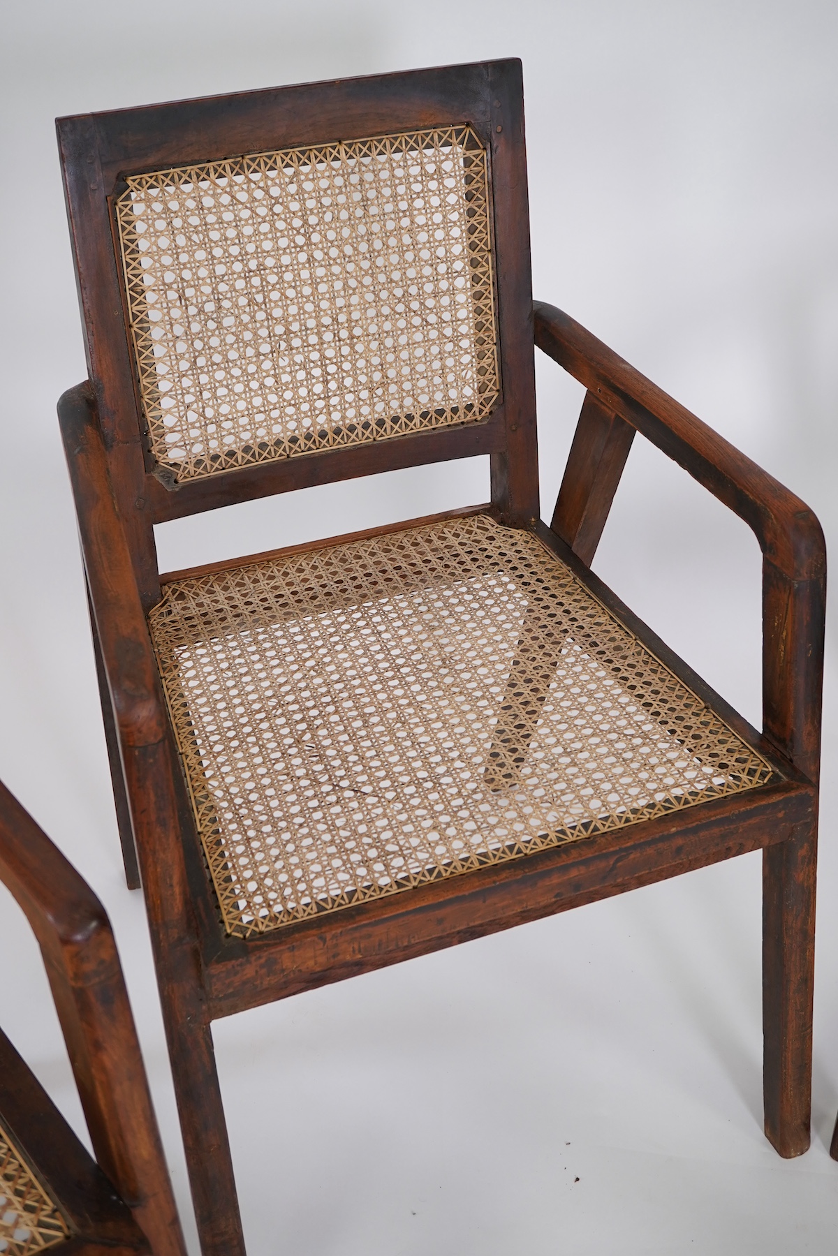 Manner of Pierre Jeanneret (Swiss, 1896-1967): A set of four solid teak and braided canework armchairs